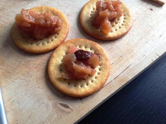 close up of cheese crackers with quince chutney on top